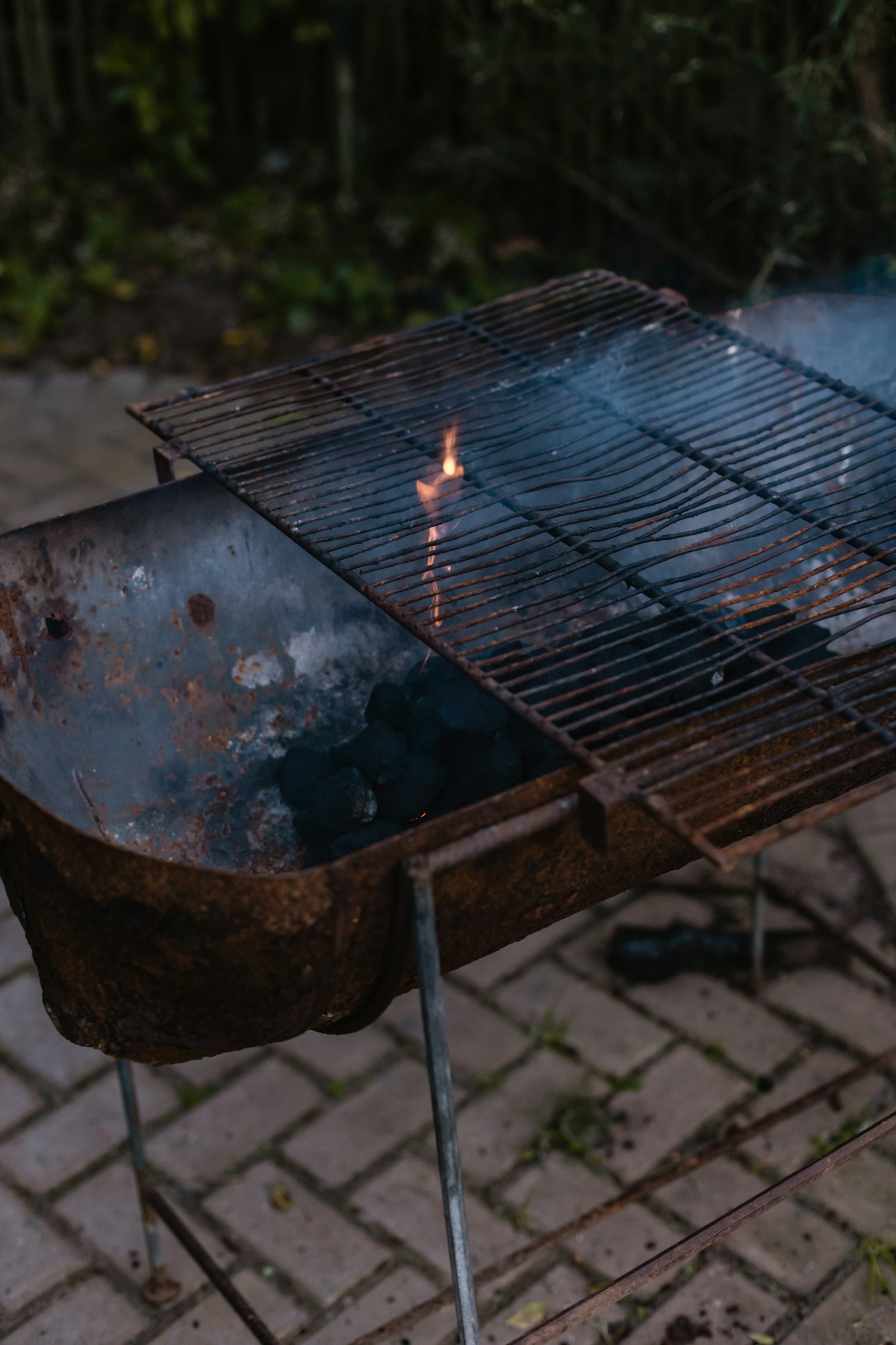 庭先でポータブル炭火グリルに串料理を焼くシーン。【画像生成プロンプト】Japanese lifestyle BBQ, subtle omotenashi styling, soft bokeh lawn, refined outdoor leisure, low saturation