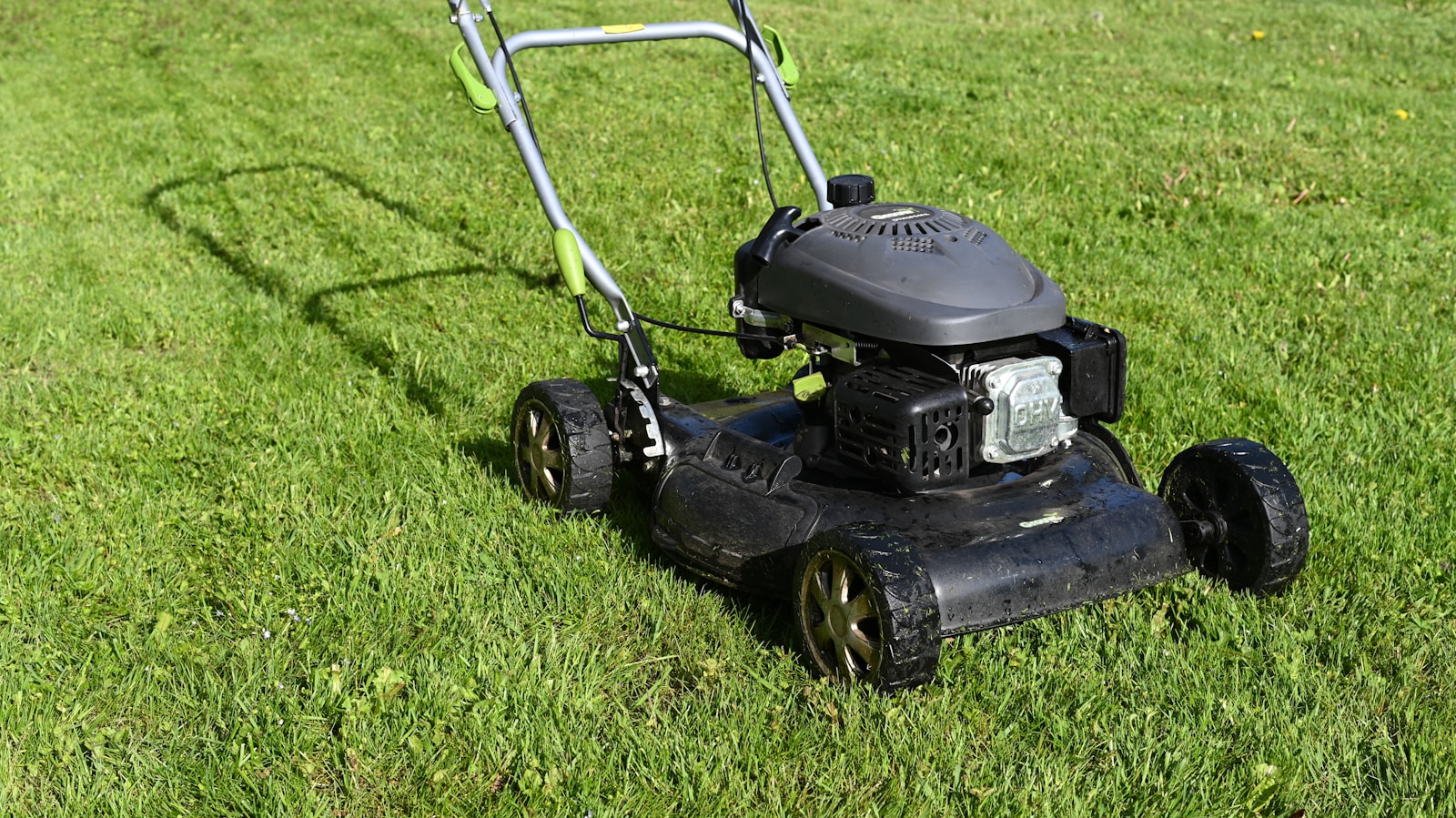 芝生を手押し式エンジン草刈機で仕上げる作業シーン。【画像生成プロンプト】Japanese corporate lawn-care hero, red mower deck, muted blue-grey grading, natural daylight, respectful documentary tone, no clutter